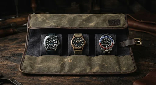Heavyweight waxed olive canvas watchmaker roll open with pockets containing three mechanical timepieces on micro-suede lining.
